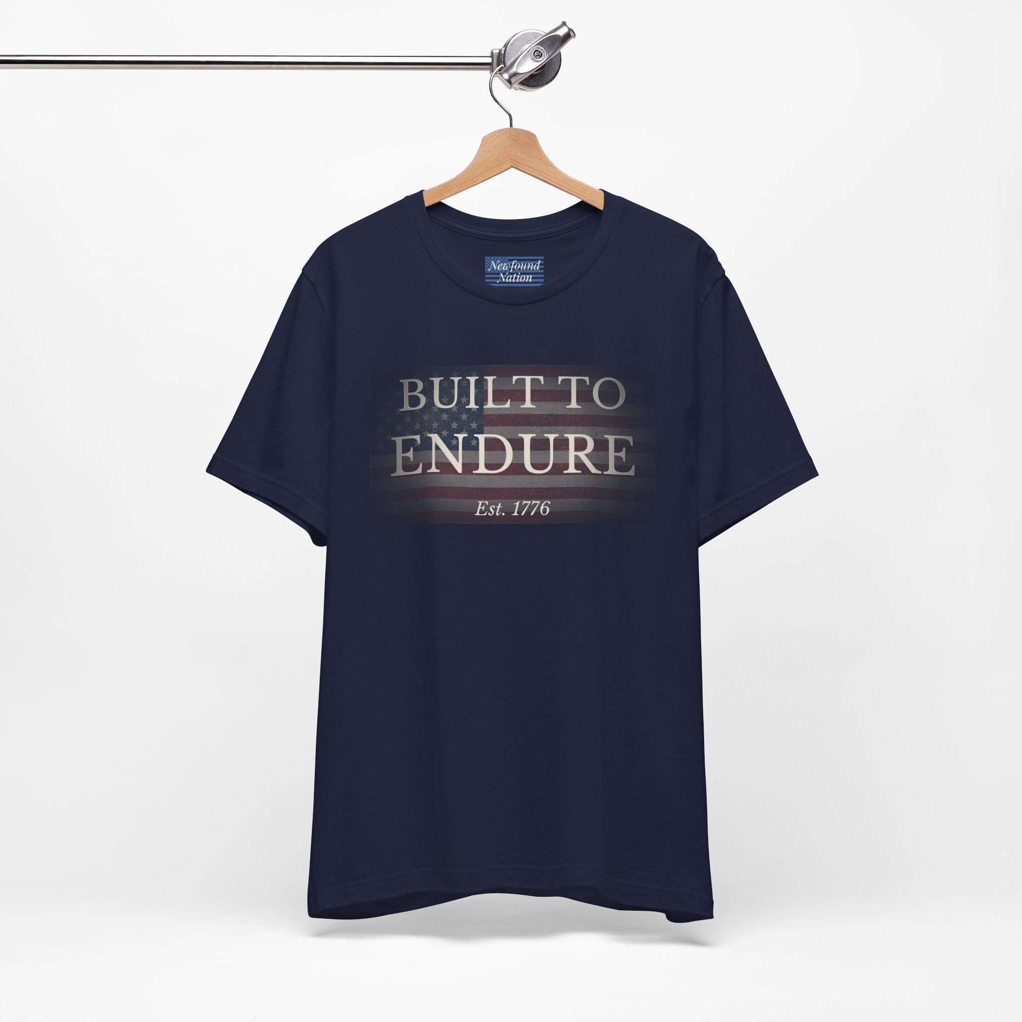 Built to Endure T-Shirt - Patriotic Est. 1776 Tee displayed on a hanger with minimalist design.